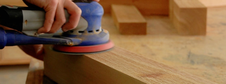 Orbital-sander-sanding-rough-cedar-4x4-on-workbench