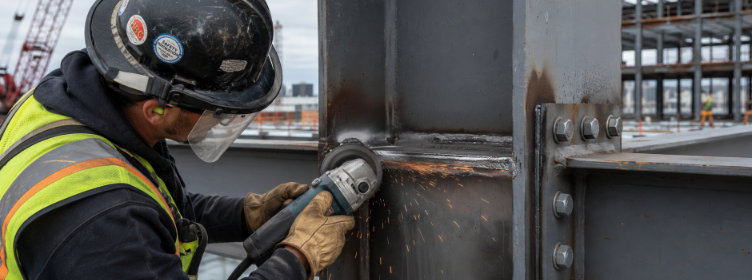 Construction-worker-grinding-structural-beams-with-angle-grinder